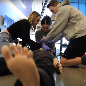 Students practice CPR on a training mannequin.